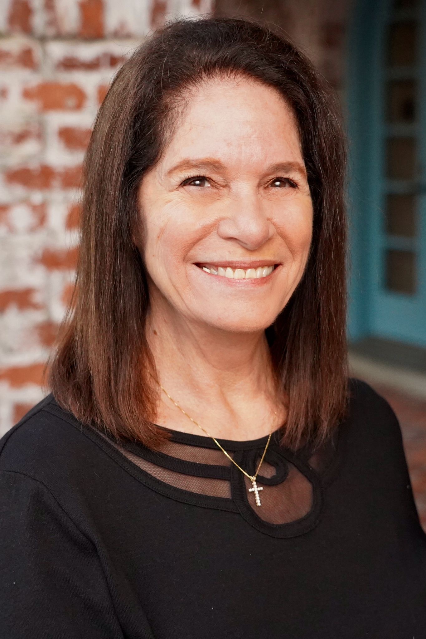 A woman with short hair smiling at the camera, wearing a black top.